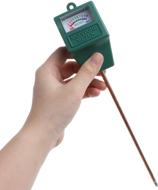 Hand die een groene vochtigheidsmeter vasthoudt met koperen pen en wijzerplaat.