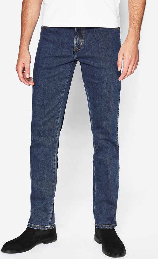 Blauwe Wrangler jeans, regular fit, gedragen met witte T-shirt en zwarte laarsjes, close-up van de benen.