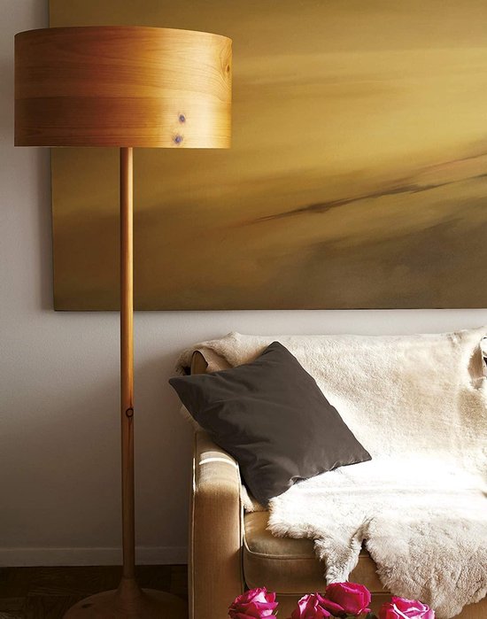 Moderne woonkamer met een bruine bank, een schapenvacht, een staande lamp van hout en een schilderij.