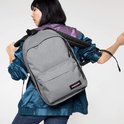 Vrouw met grijze Eastpak rugzak op haar schouder, draagt kleurrijk jack.