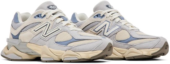 Paar beige en lichtblauwe New Balance sneakers met opvallende zolen en witte veters.