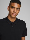 Zwarte polo met korte mouwen, gedragen door een man. Close-up van het Jack & Jones logo op de borst.