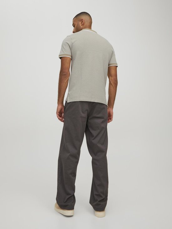 Man draagt de achterkant van een lichtgrijs poloshirt met beige kraag en manchetten met witte bies.
