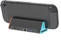 Zwarte docking station met oranje en blauwe uiteinden, met Switch 2 console erop. Toont USB 3.0 poorten, LAN, HDMI en USB-C poorten.