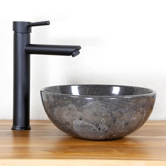 Baignoire en marbre gris foncé avec robinet noir mat.