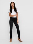 Model met lang, donker haar draagt een strakke zwarte jeans met een witte top.