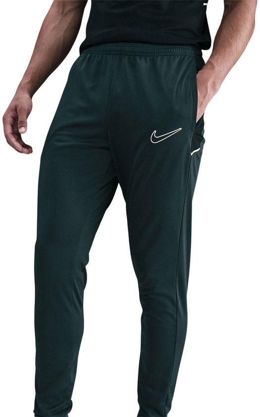 Donkergroene Nike trainingsbroek met witte swoosh op de linker broekspijp.