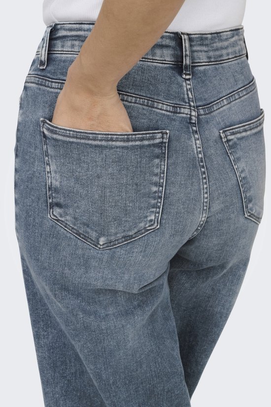Dichtbij van de achterkant van een lichtblauwe spijkerbroek met wijde pijpen. Een hand steekt in de zak.