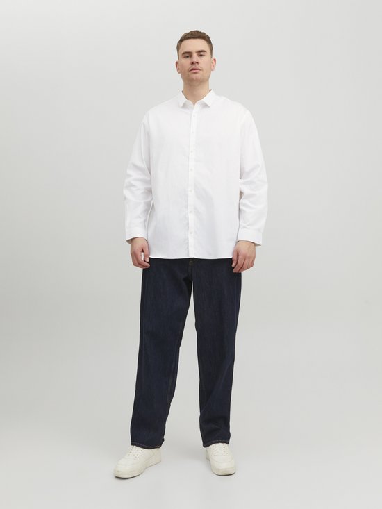 Man draagt een wit Jack & Jones overhemd en donkere jeans.
