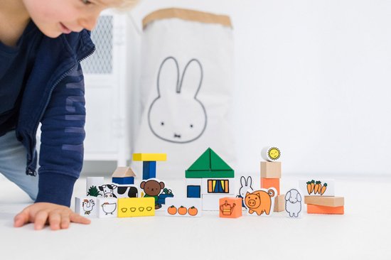 Kind speelt met houten boerderijblokken, inclusief Miffy, boerderijdieren en huizen.