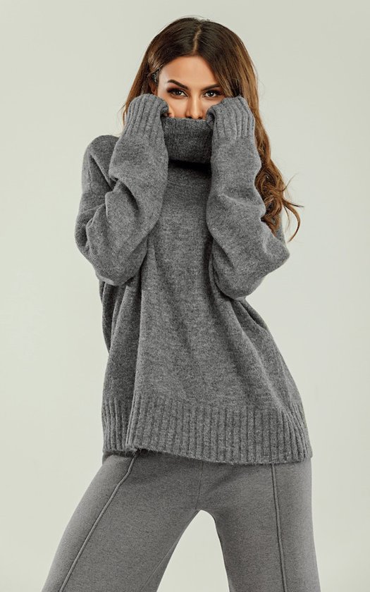 Model met gezicht half verborgen in de col van een oversized grijze gebreide trui.