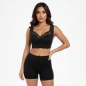 Vrouw met bruin haar, zwarte kanten bralette en zwarte shorts.
