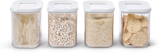 Quatre boîtes de rangement transparentes avec couvercles blancs. De gauche à droite : nouilles de riz, orge, riz blanc et chips.