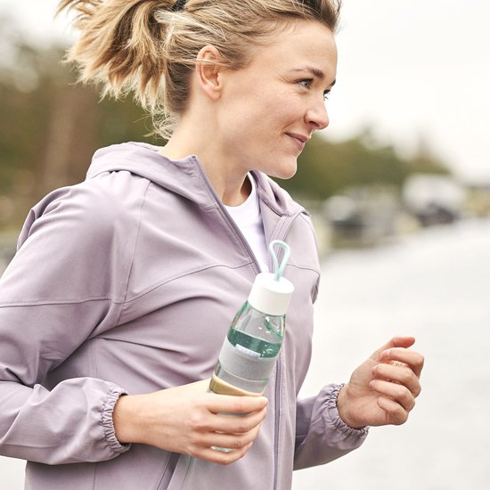 Vrouw in paars jack met een Mepal waterfles met witte dop en groene band tijdens het sporten.