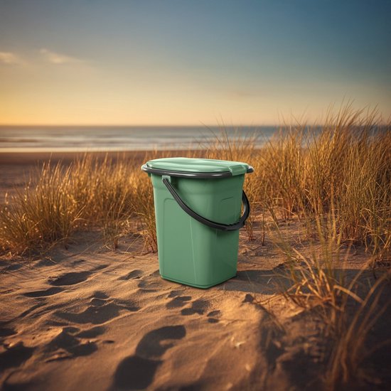 Groene campingtoilet emmer met deksel en handvat, staand op het zand op het strand.