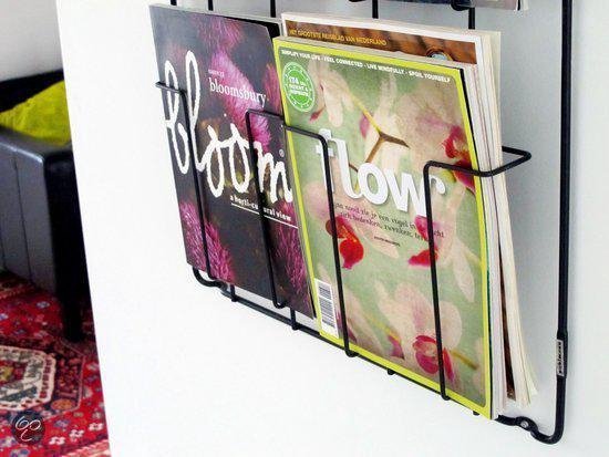 Close-up van de onderste vakken van een zwart tijdschriftenrek met twee tijdschriften: 'bloom' en 'flow'.
