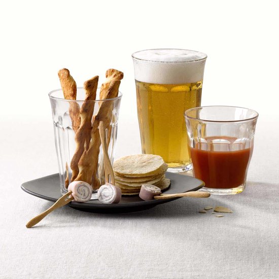 Trois verres Duralex Picardie transparents avec cannelures verticales, un avec de la bière, un avec du jus de tomate, un vide.