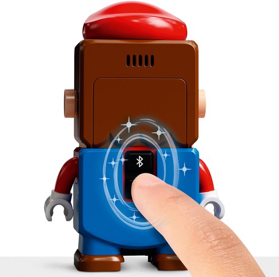 Vinger drukt op de Bluetooth-knop van de LEGO Mario-figuur, met lichteffecten.