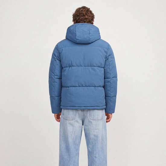 Achterkant van een blauwe pufferjas met capuchon, gedragen door een man met spijkerbroek.