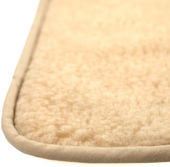 Detail van de hoek van een zachte, beige wollen onderlegger met een afgeronde afwerking.