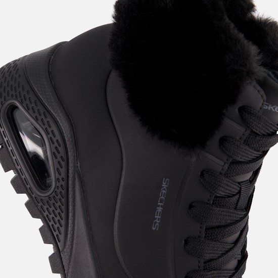Detailopname van de zwarte Skechers Uno Rugged met imitatiebont en zichtbare Air-unit in de zool.
