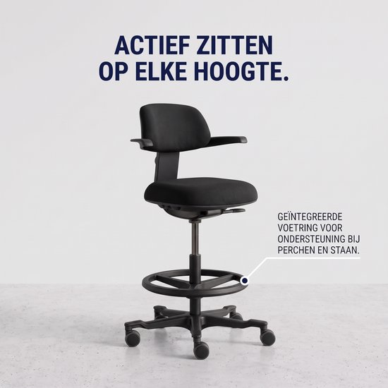 Zwarte bureaukruk met een ronde voetsteunring, op een grijze achtergrond. "Actief zitten op elke hoogte" is op de muur geschreven.