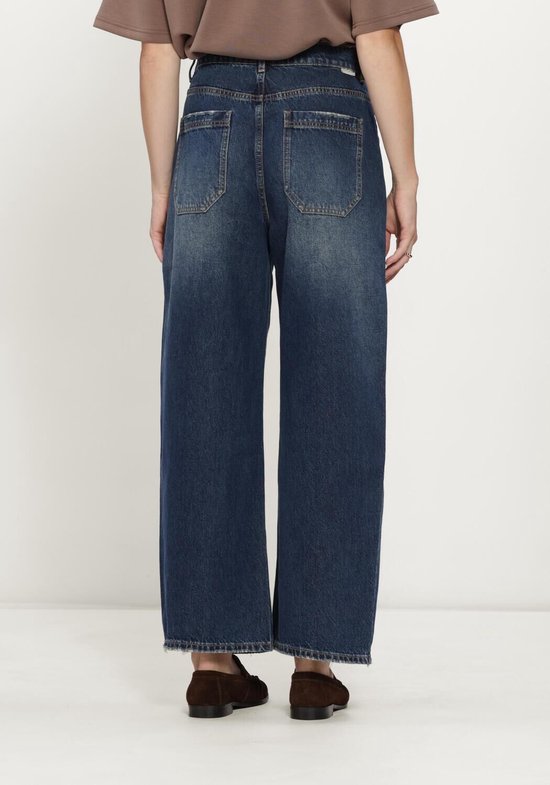 Model draagt een wijde jeans van donkerblauw denim, met een verfijnde wassing aan de achterkant.