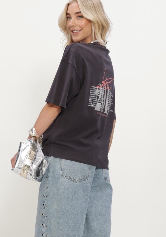 Model draagt donkergrijs tour T-shirt, achterkant met tekstprint.