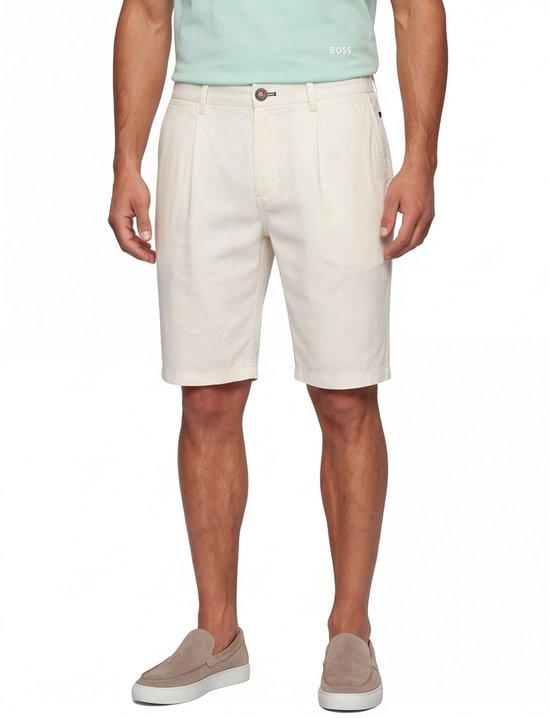 Man met gebroken witte chino shorts, lichtgroen poloshirt met 'BOSS' logo, beige instappers.