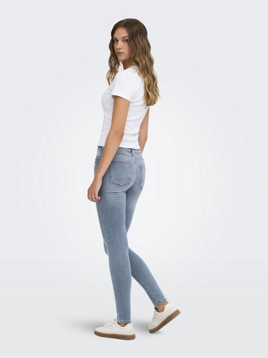 Model in een lichtblauwe ONLY skinny jeans, gezien van opzij, gecombineerd met een wit T-shirt en sneakers.