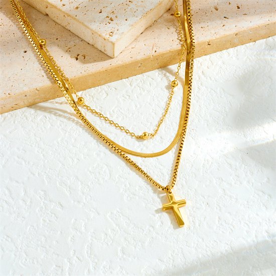 Gouden multistraks ketting met kruishanger in close-up.