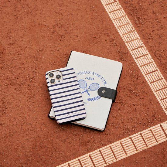 iPhone 13 hoesje met marineblauwe strepen en een notitieboekje met tennisschoenen.
