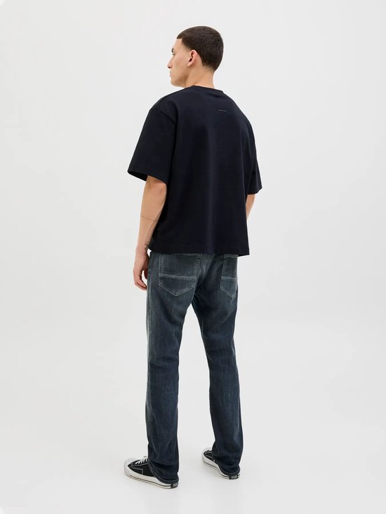 Model met donkere jeans en zwarte oversized T-shirt, rug zichtbaar.