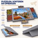Grijze puzzelmat met molenlandschap, bloemen en 6 lades vol puzzelstukjes.