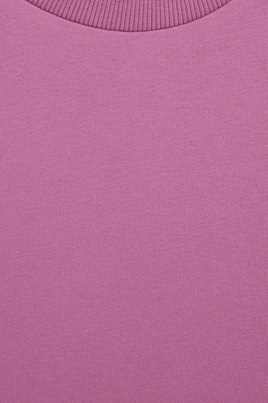 Close-up van de roze gladde stof en de geribbelde halslijn van een sweatshirtjurk.