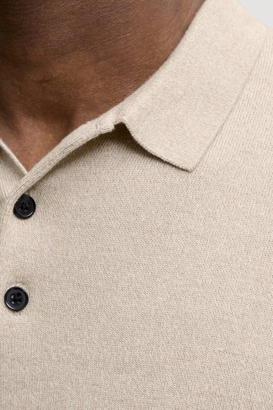Close-up van de kraag en knopen van een beige gebreide polo.