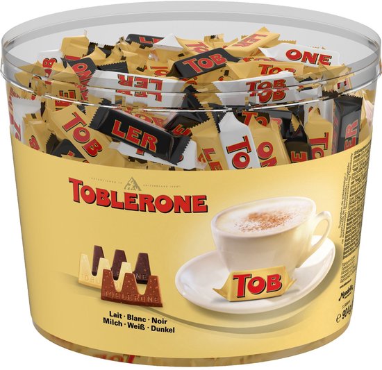 Transparante emmer met 904g Toblerone mini's: melk, wit en puur. Verpakking toont koffiekopje en chocoladestukjes.