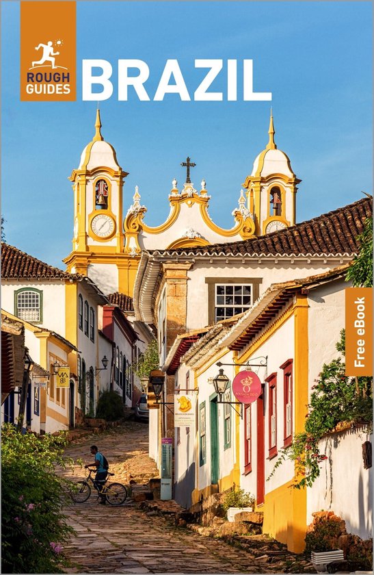 Boekcover: Rough Guides Brazil, met een geplaveide straat, gekleurde huizen en een kerk in de verte. Een fietser rijdt de straat op.