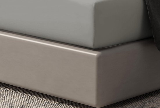 Gros plan d'un drap-housse gris clair tendu sur une base de lit grise.