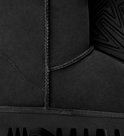 Detailopname van de zwarte suède afwerking, stiksels en zool van de UGG-laars.