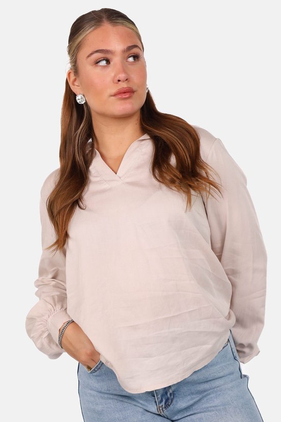 Close-up van een model in een beige blouse met V-hals en pofmouwen.