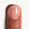 Een duim met een lichte, roze nagellak met een glanzende afwerking.
