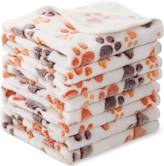 Een stapel van vier zachte, witte fleece dekens met een patroon van oranje en grijze pootafdrukken.
