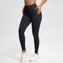 Zwarte sportlegging met hoge taille en witte sneakers, zijaanzicht.