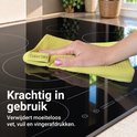 Hand veegt een glanzende kookplaat schoon met een gele Clean Dry microvezeldoek.
