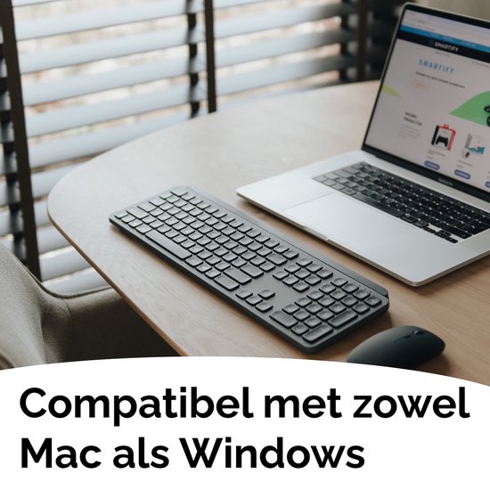 Donkergrijs Smartify draadloos toetsenbord op een houten tafel naast een zilverkleurige laptop met een website.