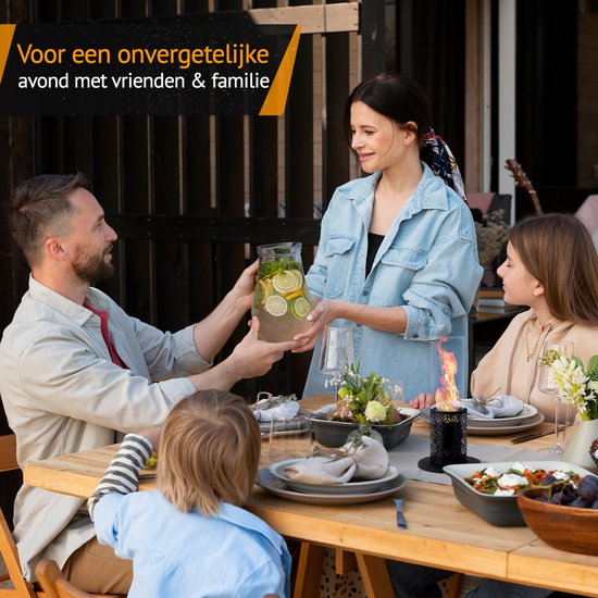 Gezin en vrienden genieten van een maaltijd buiten, met een sfeerhaard met vlammen op tafel. Tekst: "Voor een onvergetelijke avond met vrienden & familie".