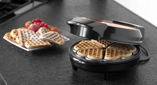 Een Bestron hartjeswafelijzer met verse wafels. Een bord met wafels en fruit staat ernaast.