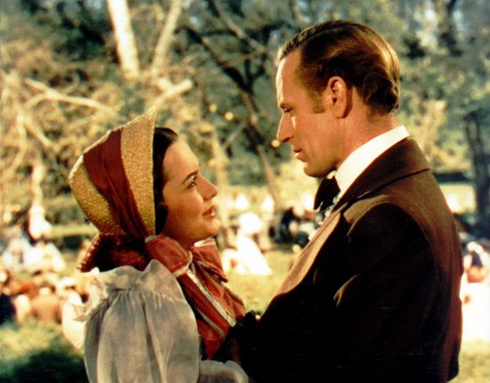 Scarlett O'Hara met gestreepte hoofddoek, kijkt naar een man in een donker pak buiten.