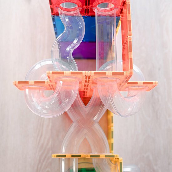 Een ingewikkelde constructie van doorzichtige buizen met rode en blauwe magnetische tegels.